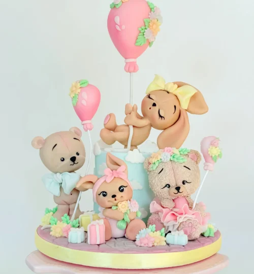 tort kus on neli suhkrumassist looma. Jänes ripub õhupalli küljes, jänes istub käes on lilled, karvane karu satsiseelikuga, seisev karu suure lipsu ja õhupalliga